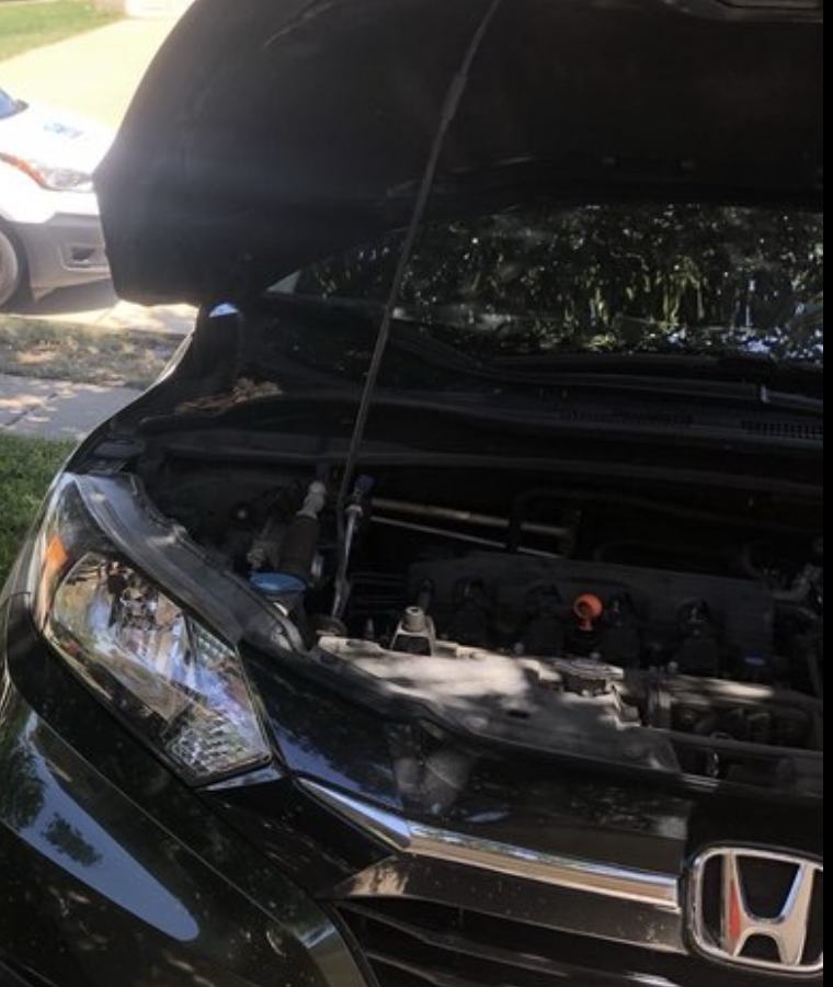 A black Honda HR-V with its hood up, parked on a residential street